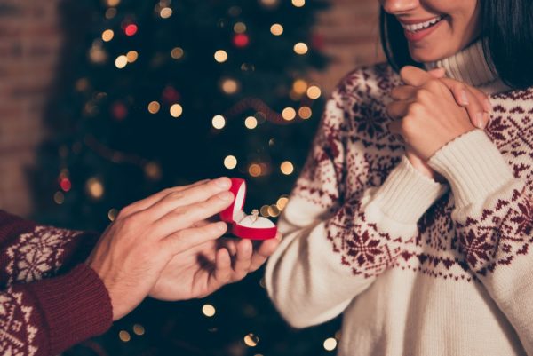 man proposing to woman in front of christmas tree