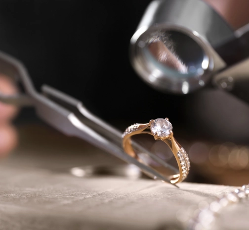 jeweler examining gold diamond ring with a loupe to buy the gold and diamonds
